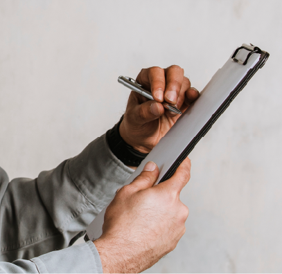 A man's hands holding a pen to a clipboard